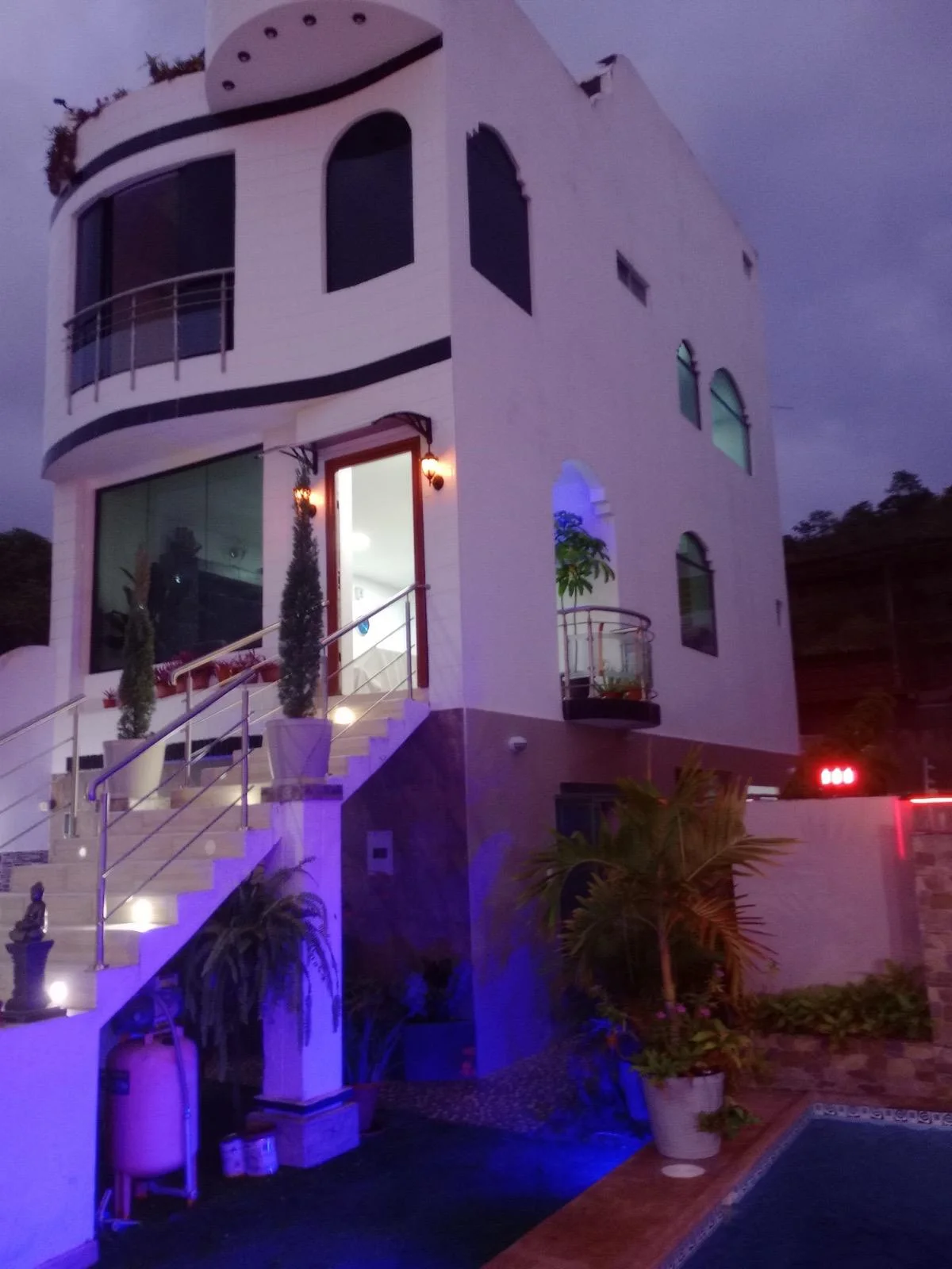La casa iluminada de noche, junto a la piscina